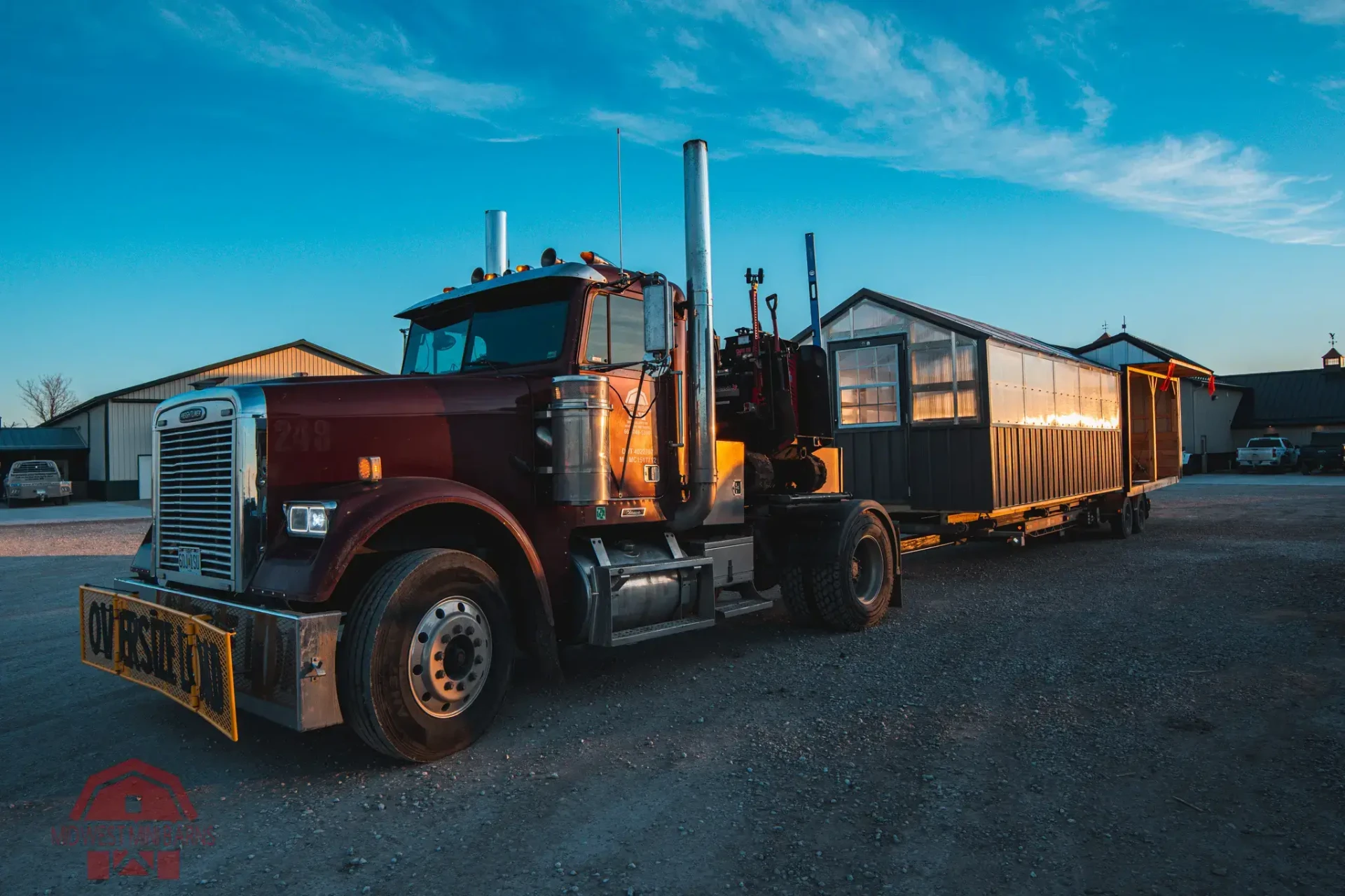 Midwest Mini Barns delivery truck hauling a building at sunrise