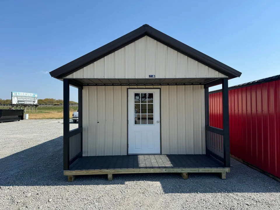 Front view of cream-colored metal cabin with black roof, dark porch railings, and covered six-foot porch