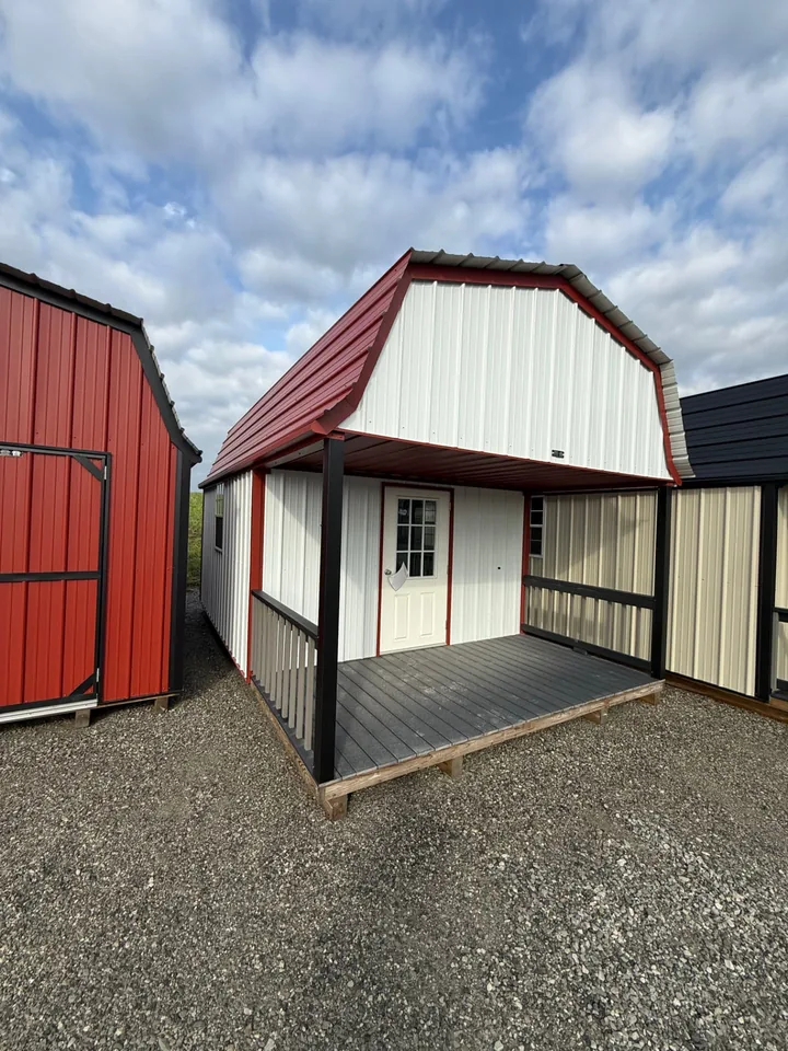 Red and white metal barn-style cabin with covered porch, white entry door, and dark decking