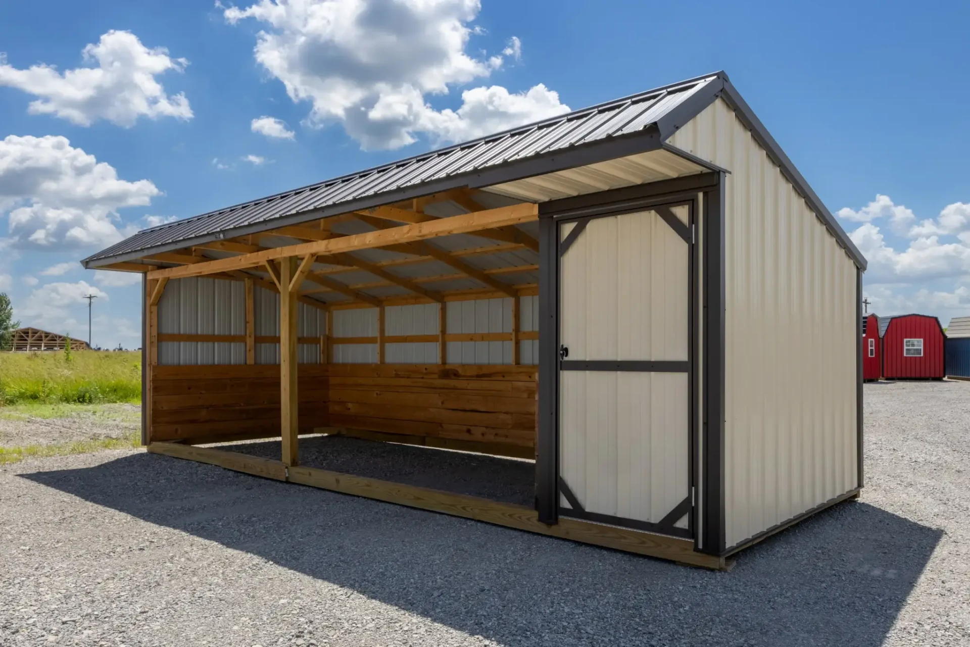 Tan run-in horse shelter with open front, wood kickboards, and a metal roof